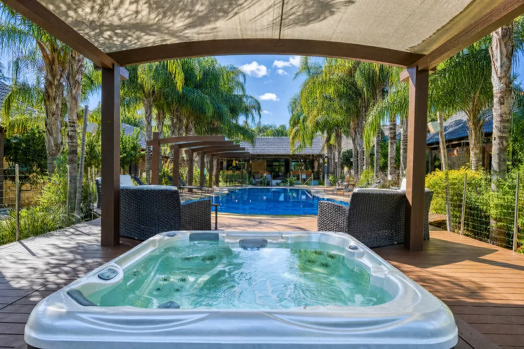 Jacuzzi under a pergola facing the pool